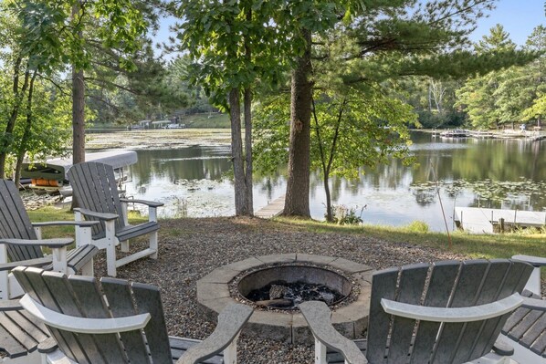 A lakeside seating area with Adirondack chairs and a fire pit. - Peaceful Cabin on Whitefish Chain (Crosslake)