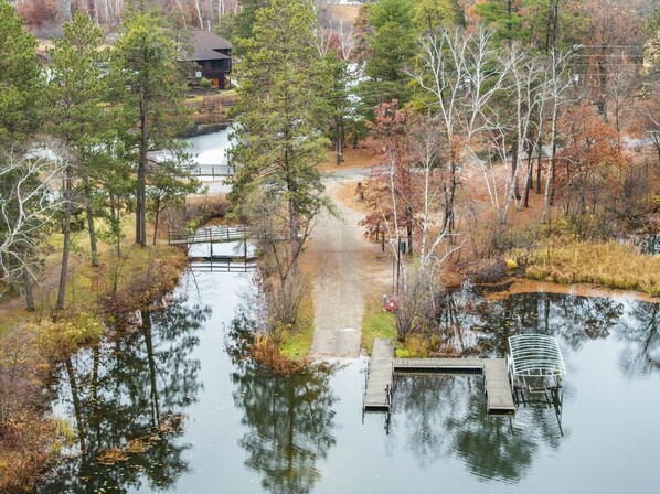 A tranquil lakeside setting with a dock, a pathway, and a building in the background. - Peaceful Cabin on Whitefish Chain (Crosslake)
