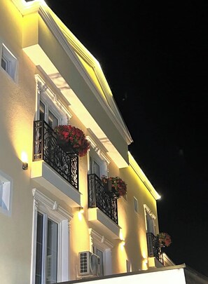 Un immeuble à plusieurs étages doté de balcons, éclairé par un éclairage chaleureux, et dont les unités de climatisation sont installées à l’extérieur.