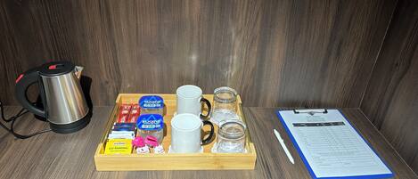 Una bandeja con una tetera, tazas, tarros y un menú sobre una mesa de madera.
