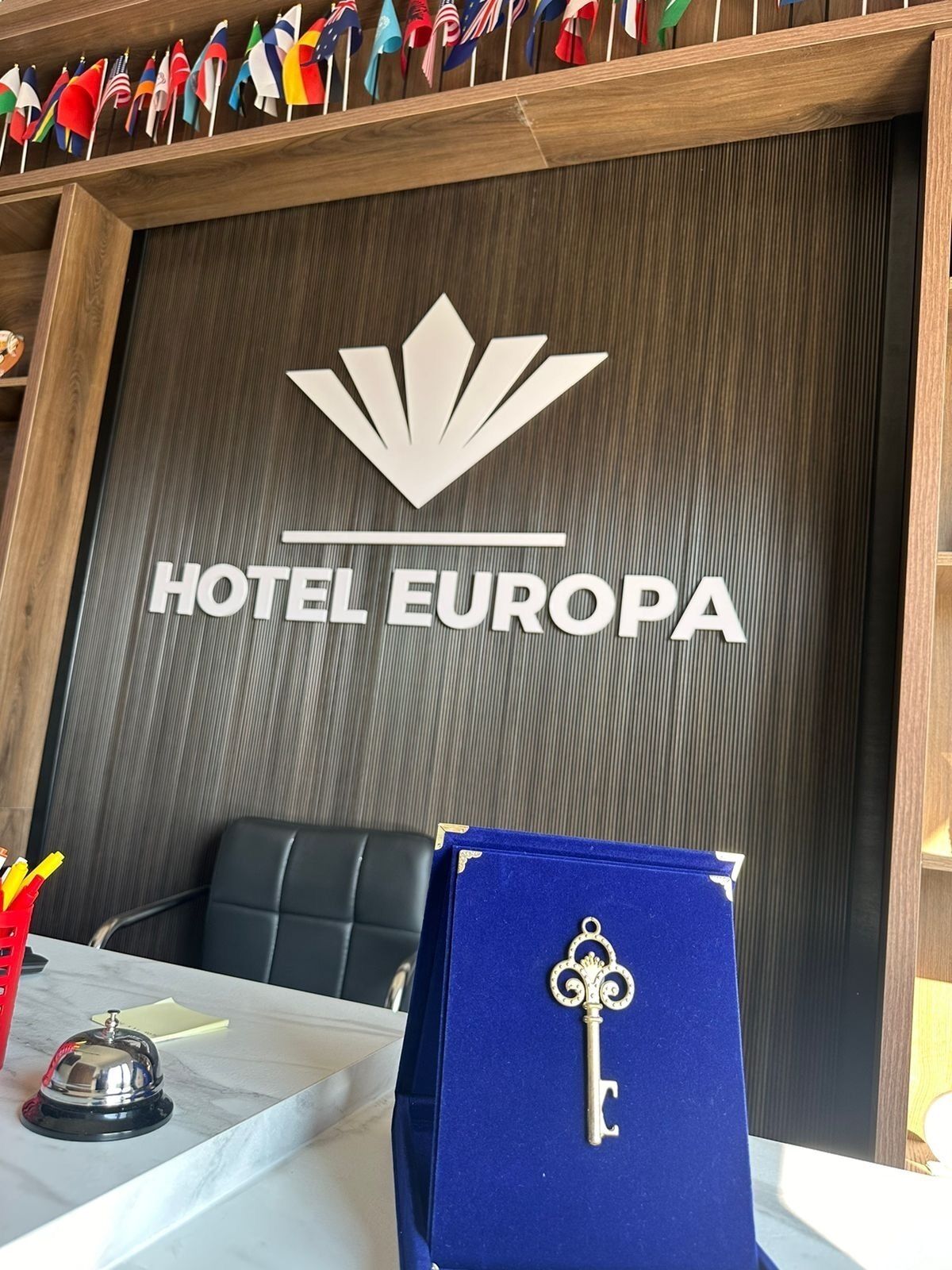A reception desk with a sign reading "HOTEL EUROPA" and a key on a blue box.