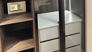 Een inloopkast met houten planken, een kledingroede en een inbouwkluis.
