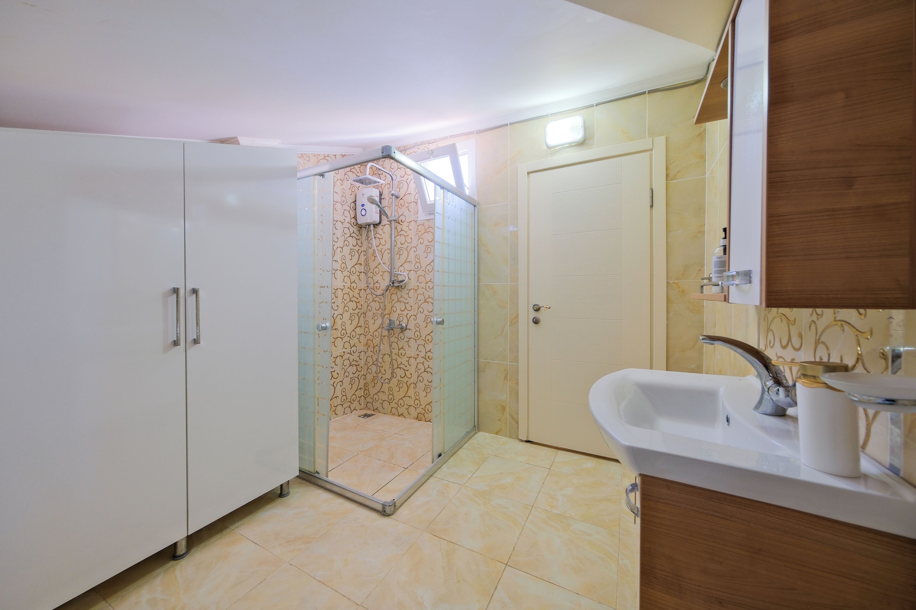 A bathroom with a glass-enclosed shower, a sink with a mirror, and a cabinet.