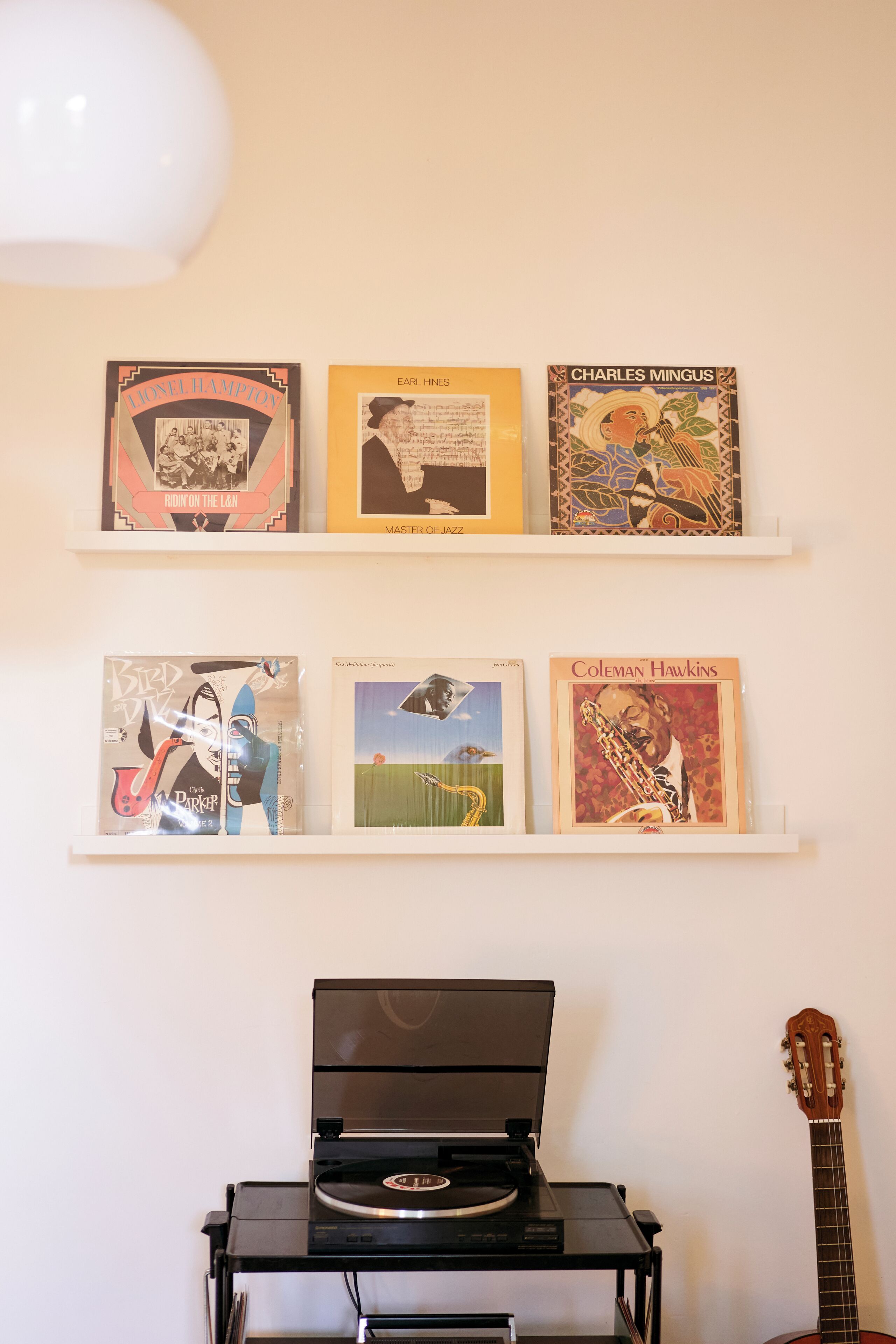 A wall with two shelves displaying vinyl records and a turntable.