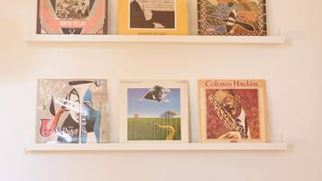A wall with two shelves displaying vinyl records and a turntable.