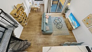 A spacious living area with a sofa, coffee table, and a dining table. There is a staircase on the left and a view of the outside through a window. - Nature Views Washer, Dryer, Balcony 1 Purg #6 (Vernon)