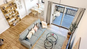 A modern living room with a grey sofa, wooden floor, and a dining area with a table and chairs. - Nature Views Washer, Dryer, Balcony 1 Purg #6 (Vernon)