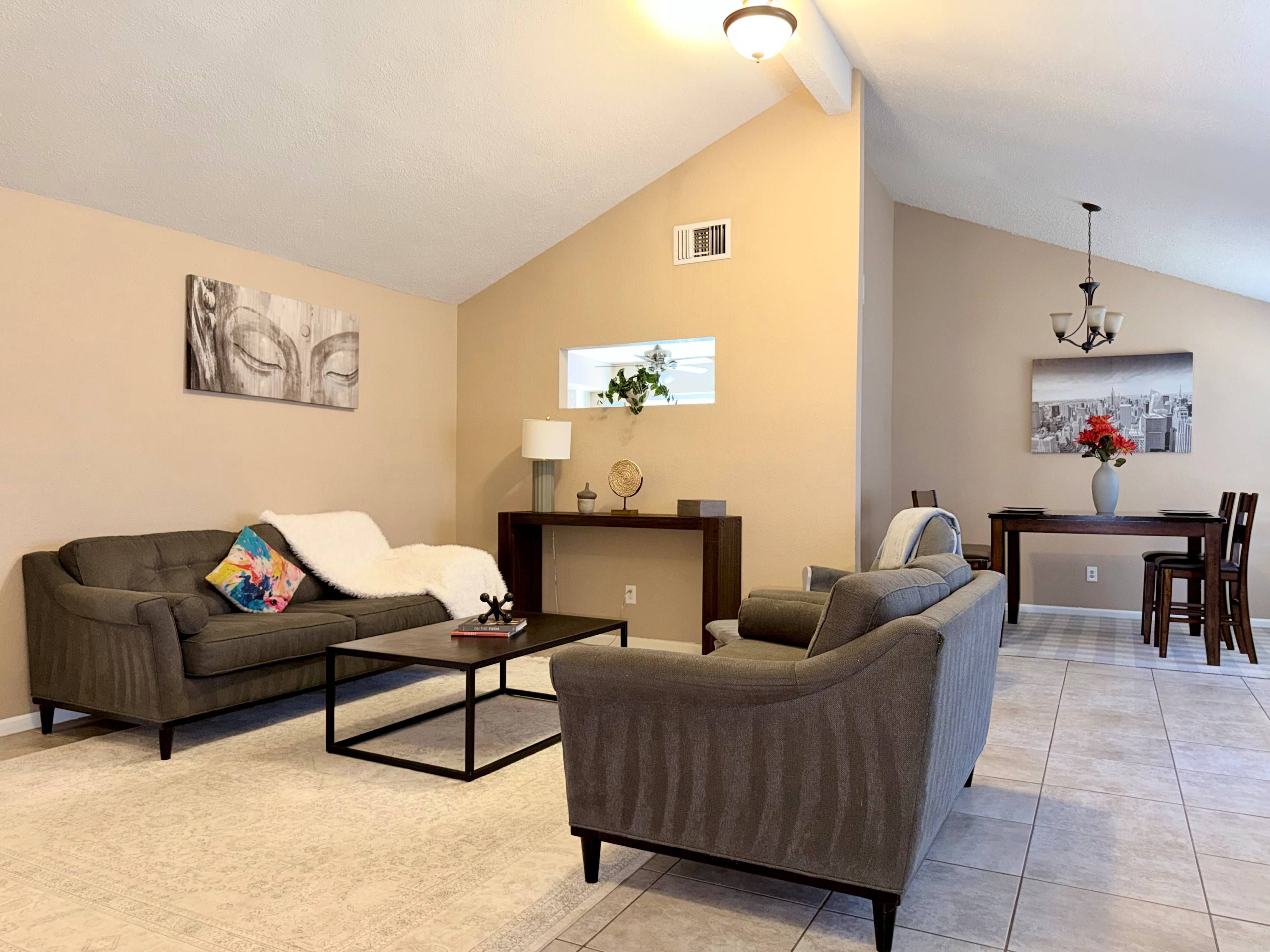 Una sala de estar con sofá, sillón, mesa de centro y comedor con mesa y sillas.