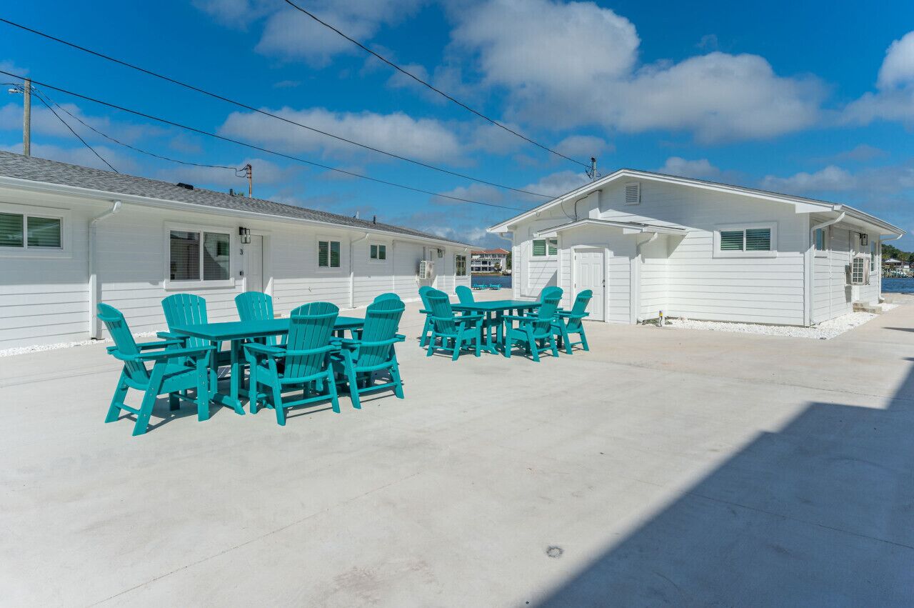 Una casa móvil blanca con un patio que incluye sillas turquesa y una mesa.
