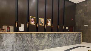 A reception area with a marble counter, framed portraits on the wall, and a reception desk. - Rafef Aldyafa hotel (Makkah)