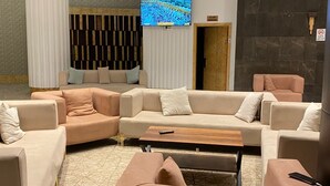 A modern living room with a sectional sofa, a coffee table, and a flat-screen TV mounted on the wall. - Rafef Aldyafa hotel (Makkah)