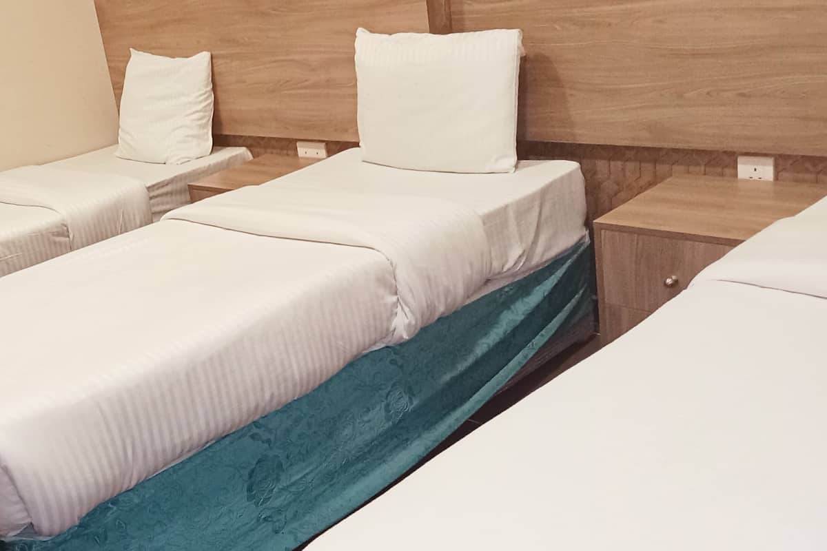 A hotel room with two single beds, each with a pillow and a wooden headboard.