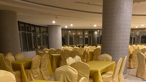 A banquet hall with multiple tables covered in yellow tablecloths and chairs, large columns, and a tiled floor. - Rafef Aldyafa hotel (Makkah)