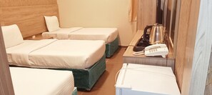 A hotel room with two beds, a desk with a telephone and kettle, and a small table. - Rafef Aldyafa hotel (Makkah)