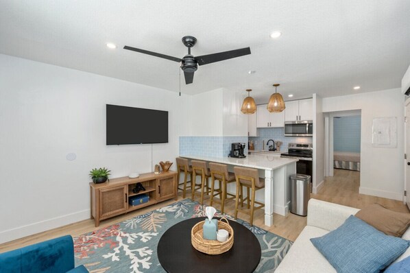 Una cocina moderna con barra, ventilador de techo y televisor de pantalla plana montado en la pared.