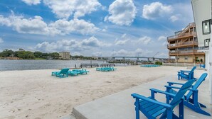 A beach with blue Adirondack chairs and a concrete walkway. - Unit #5 Waterfront + Heated Pool and Spa Access (Fort Walton Beach)