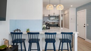 A modern kitchen with a central island, bar stools, pendant lighting, and a microwave. - Unit #5 Waterfront + Heated Pool and Spa Access (Fort Walton Beach)