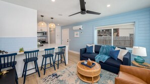 A modern kitchen with a bar area, a dark blue sofa, and a ceiling fan. - Unit #5 Waterfront + Heated Pool and Spa Access (Fort Walton Beach)