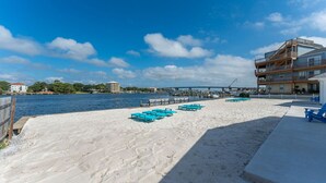 Una playa con sillas azules para tomar el sol y una terraza de madera.