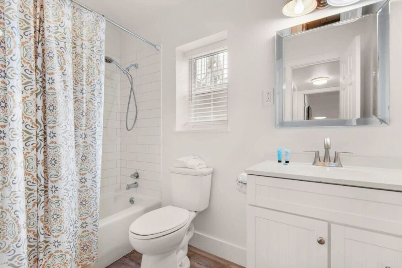 A bathroom with a shower, toilet, and a vanity with a mirror.