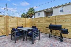 Un espace extérieur aménagé avec une table et des chaises, un barbecue et une clôture en bois.