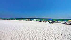 Ein Strand mit weißem Sand und klarem, blauem Wasser.