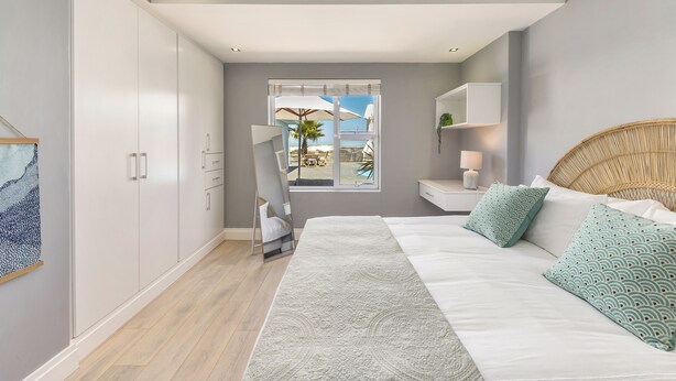 Ein Schlafzimmer mit Bett, großem Fenster, Kleiderschrank und Blick ins Freie.
