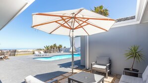Eine Terrasse mit Pool, Gartenmöbeln und Meerblick.