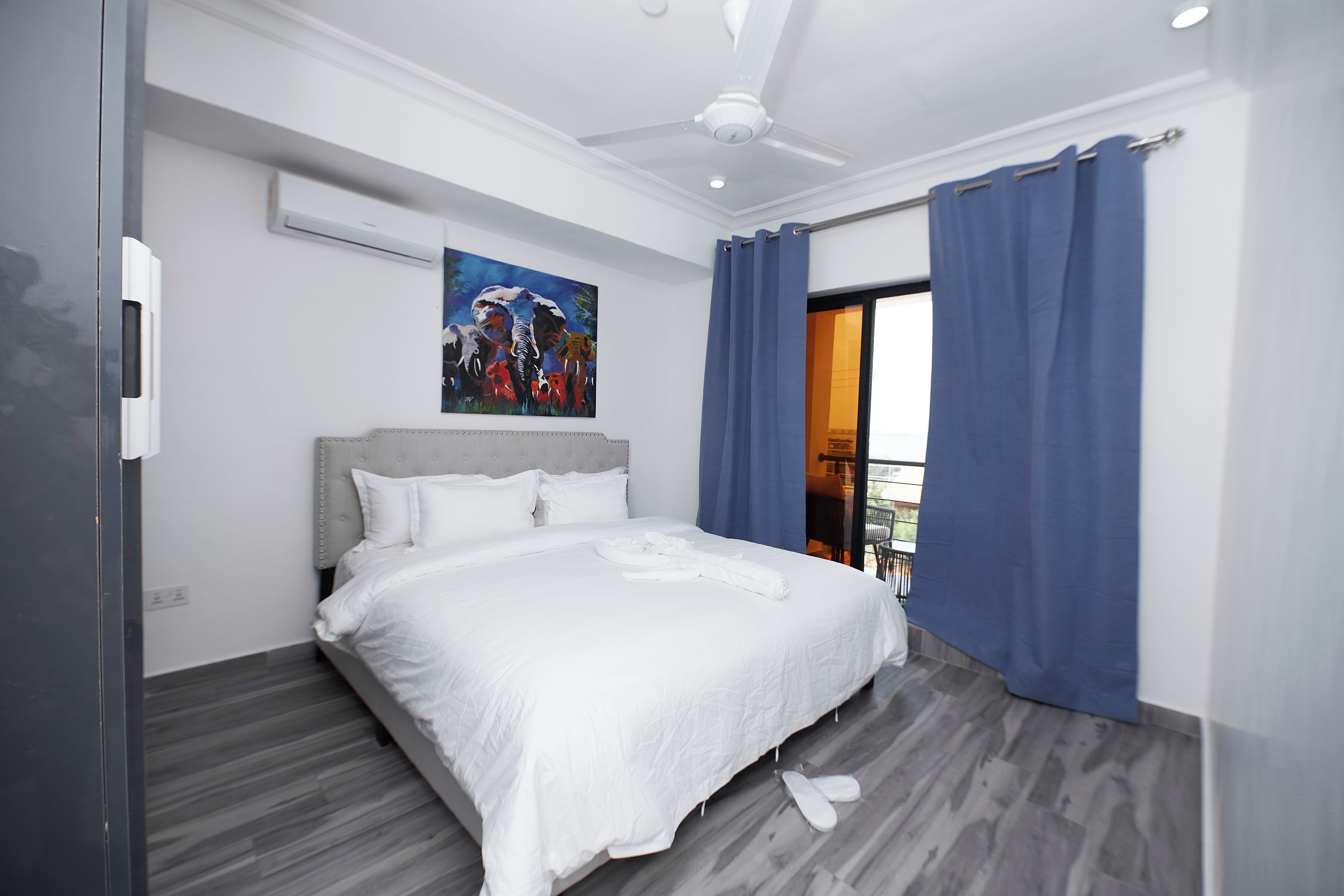 Una habitación de hotel moderna con una cama grande, un ventilador de techo y vistas al exterior.
