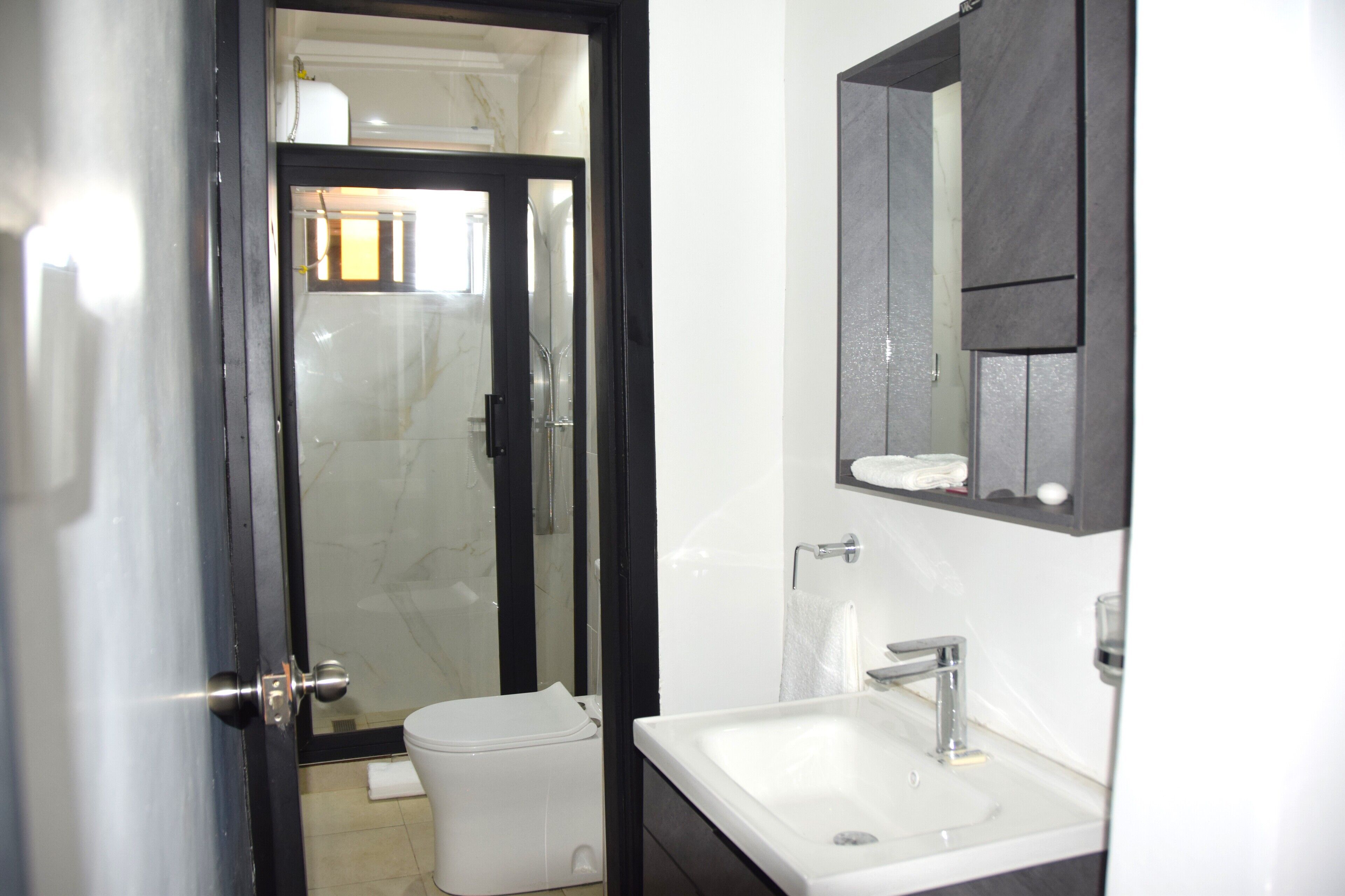 Un baño con lavamanos blanco, espejo y retrete.