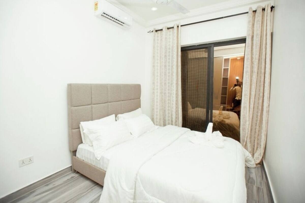 A hotel room with a bed, a wardrobe, and a sliding glass door leading to a balcony.