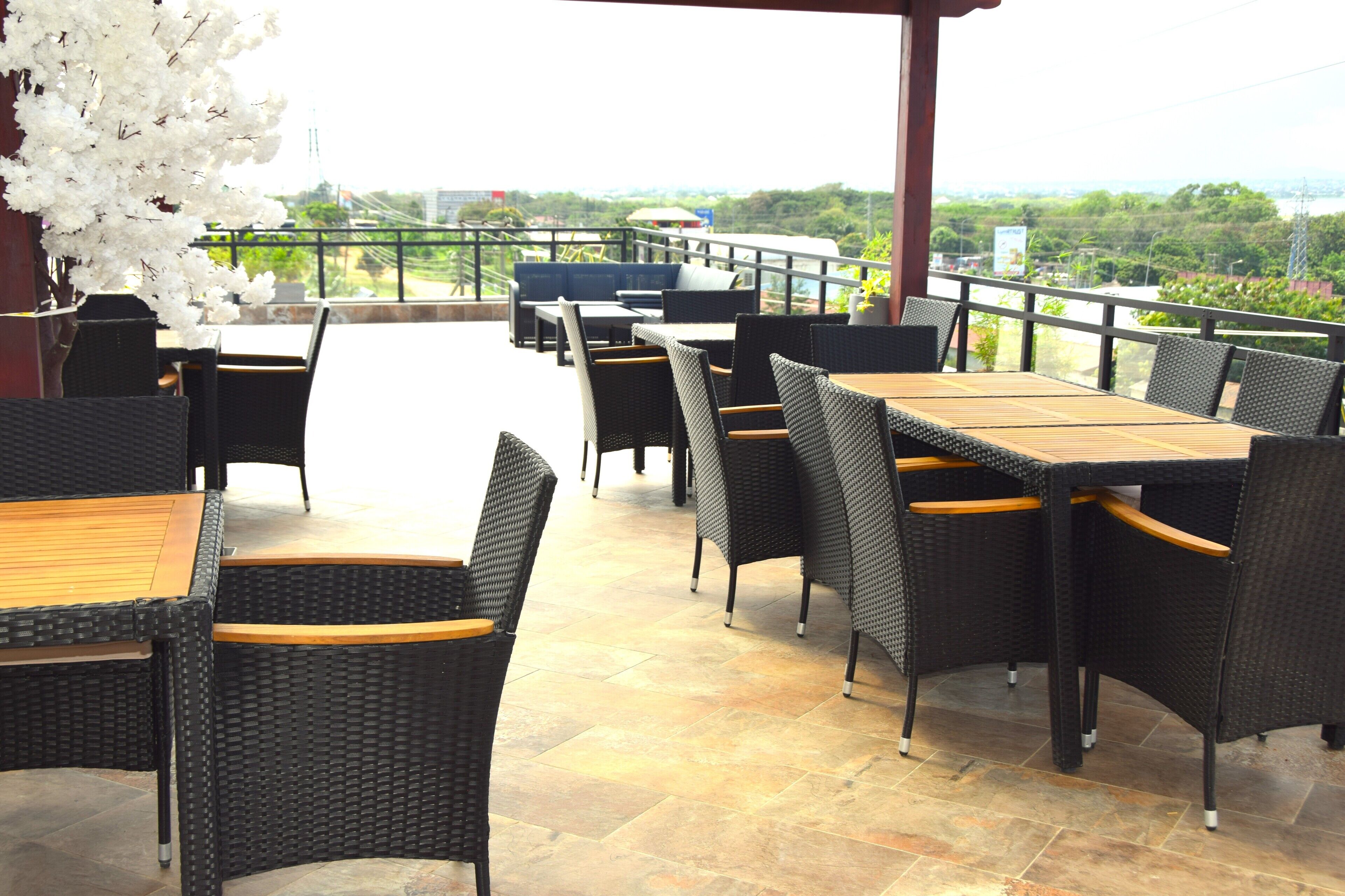 Un patio al aire libre con mobiliario de mimbre y vistas a la ciudad.