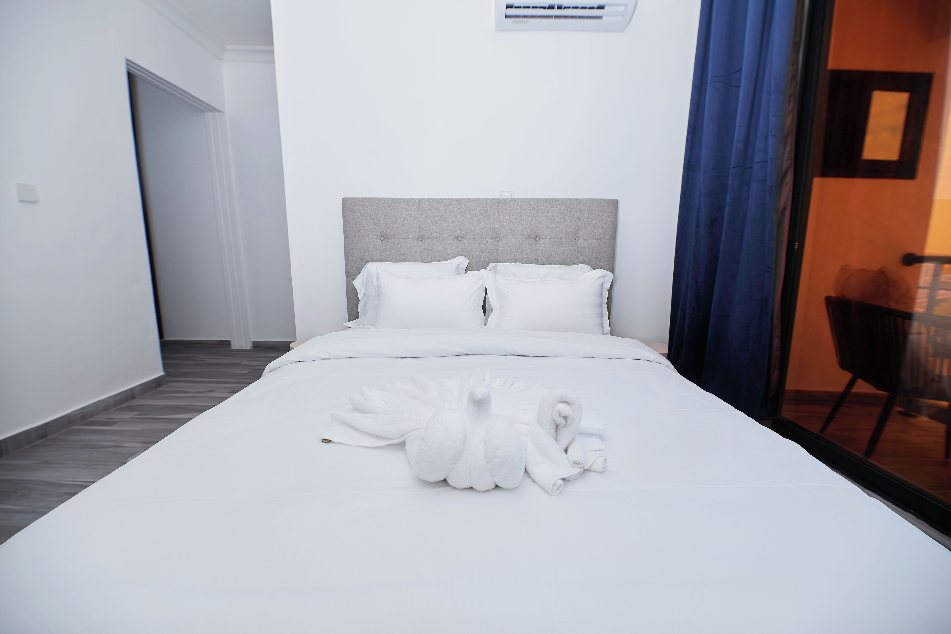 Una habitación de hotel con una cama bien hecha, cabecera y ventana con vistas.