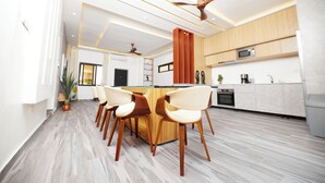 A modern kitchen with a central island, wooden chairs, and a ceiling fan. - River Hills Hotel & Suites (Mile 11)