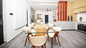 A modern kitchen with a central island, a dining area with a glass-top table, and a ceiling fan. - River Hills Hotel & Suites (Mile 11)