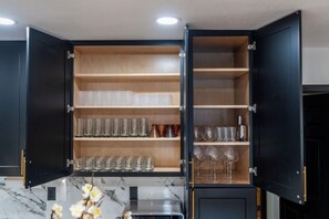 Eine Küche mit offenen Schränken, die Glaswaren zeigen, und einem eingebauten Backofen.