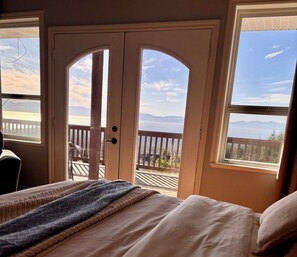 Une chambre avec un lit, une fenêtre et une vue sur une terrasse et des montagnes.