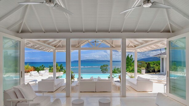 A spacious room with a large glass wall offering a view of a pool and the ocean.