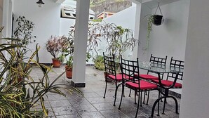 An outdoor patio with a table and chairs, surrounded by potted plants and a tiled floor. - K&K Apartments (Machico)