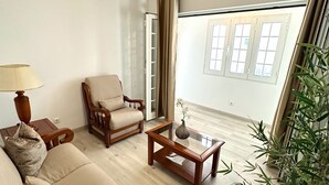 A living room with a sofa, armchair, coffee table, lamp, and a potted plant. - K&K Apartments (Machico)