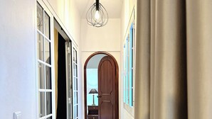 A hallway with a wooden floor, a ceiling light fixture, and a door at the end. - K&K Apartments (Machico)