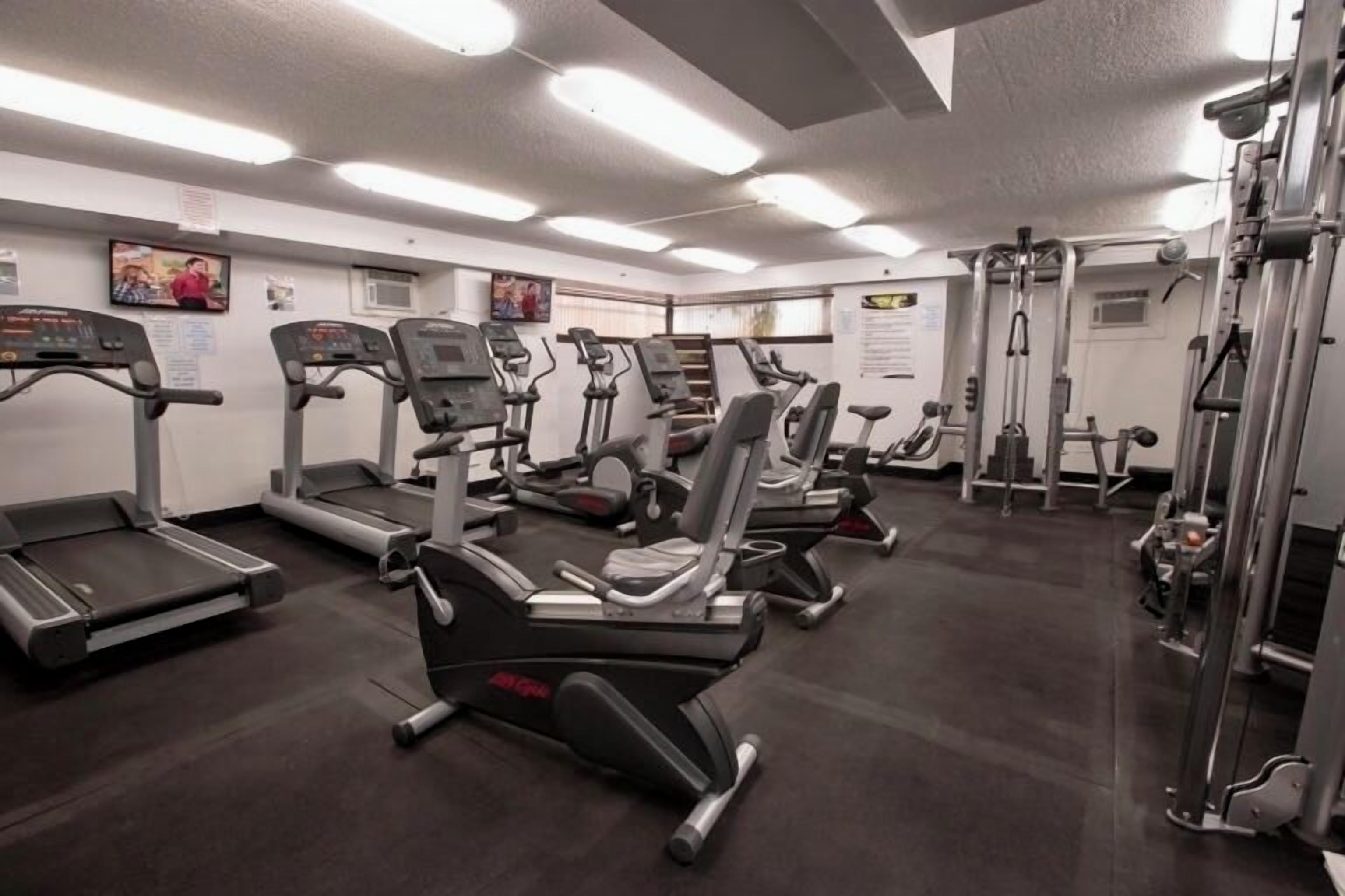 Ein Fitnessstudio mit Laufbändern, Crosstrainern und Gewichten.