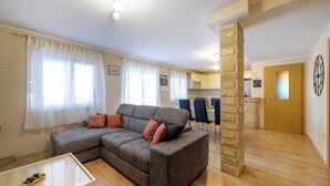 Una sala de estar con un sofá seccional gris, una mesita blanca y un pilar de piedra.