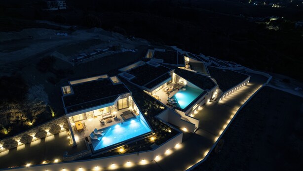 A modern resort with two swimming pools, outdoor seating, and a well-lit pathway.