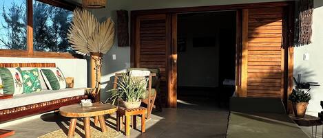 A spacious patio with a sofa, wooden table, and chairs, a bench, and a potted plant.