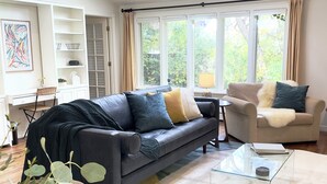 Ein modernes Wohnzimmer mit Ledersofa, Glastisch und Blick auf Grün.