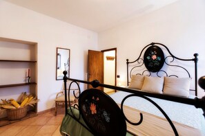 A bedroom with a metal bed frame, a wooden door, a chair, and a basket of corn on the floor. - I Castagnini
Your Corner of Tuscany: relaxation and discovery (MONTECATINI VAL DI CECINA)