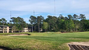 A golf course with a clubhouse, multiple buildings, and tall trees. - Quiet 3rd floor King condo Pawleys Island Golf Course WiFi, SC State Park Pass (Pawleys Island)