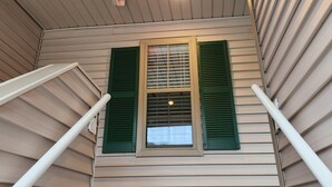 A room with a sloped ceiling, a window with green shutters, and a visible light fixture. - Quiet 3rd floor King condo Pawleys Island Golf Course WiFi, SC State Park Pass (Pawleys Island)