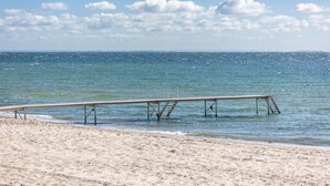 En strand med en träbrygga som sträcker sig ut i havet.